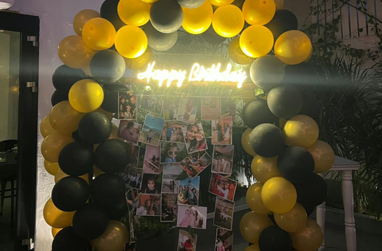 A balloon arch backdrop hung with photographs