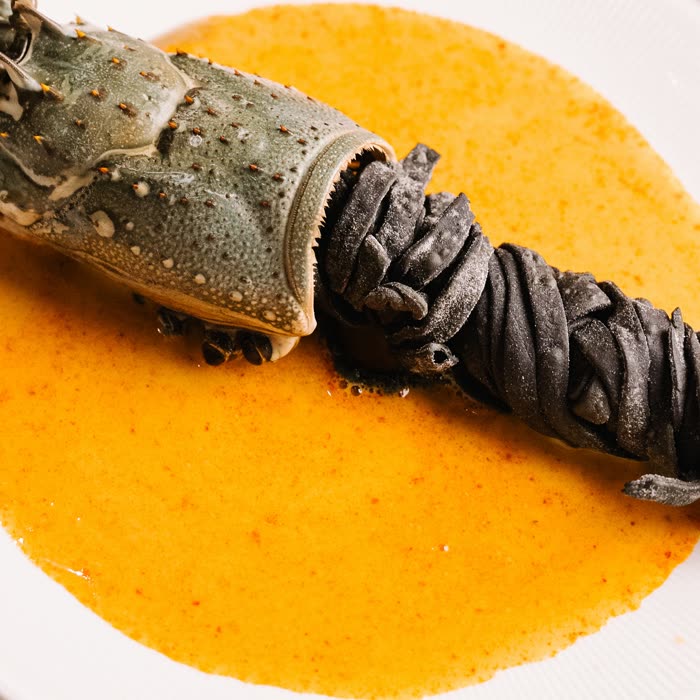 Seafood course presented in a sculpted metal gauntlet