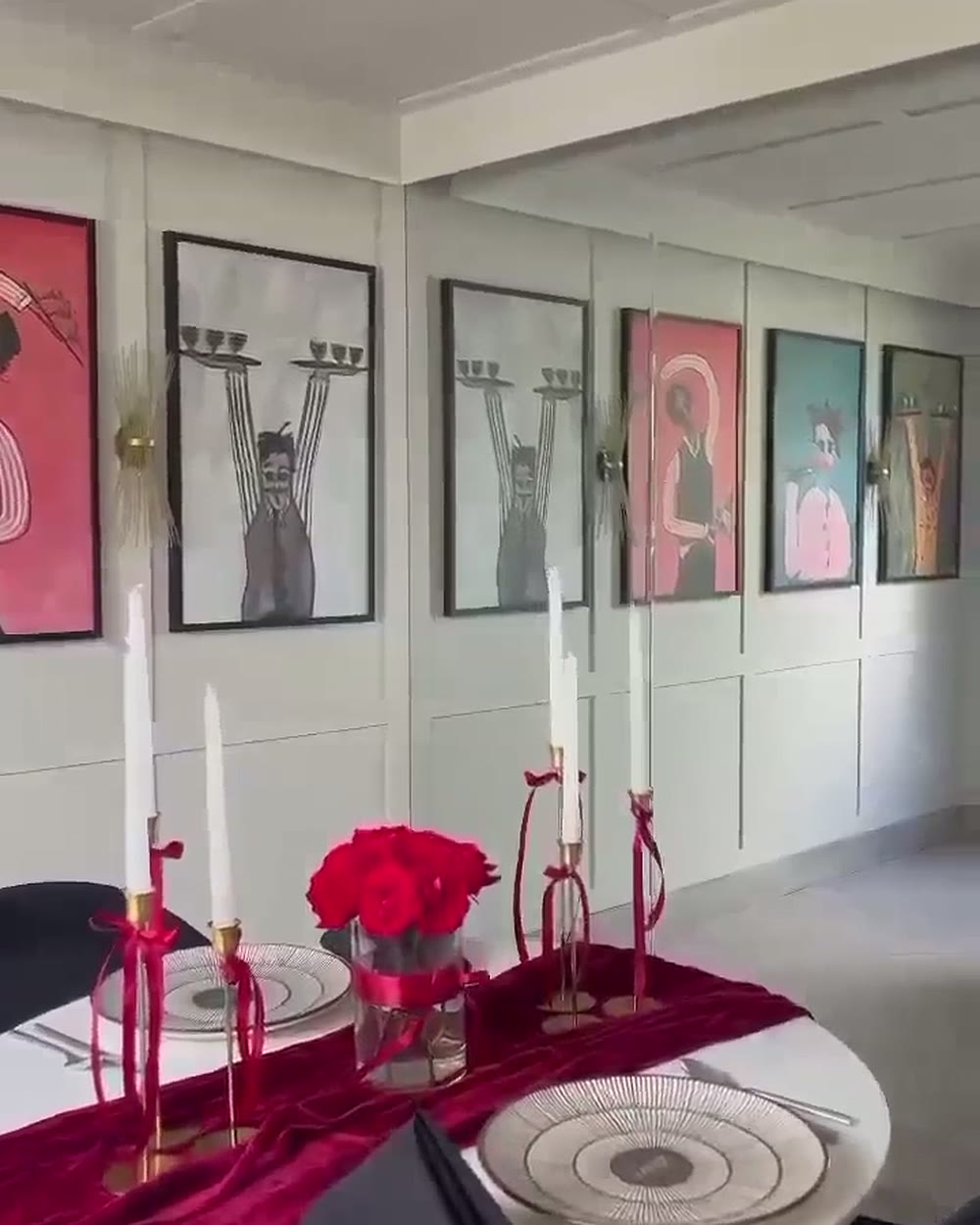 White Room hung with contemporary portraits, table dressed with a burgundy runner and red roses